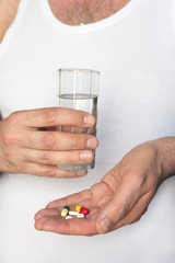 Men hands with pills and glass of water. Concept of healthcare, illness and treatment.