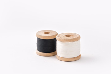 Two wooden coils with threads of black and white colours.