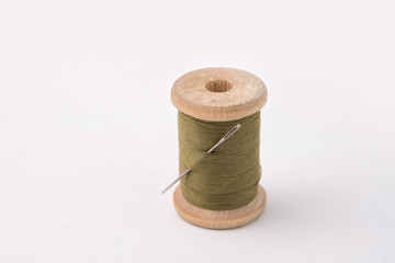 Vintage wooden coil with coiled strings of green color with needle.