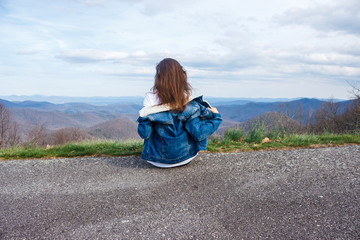 Woman traveler sits and looks at the mountains