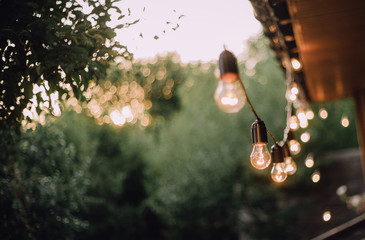retro garland lamps outside shine evening walls house © yuriy