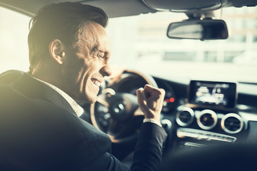 Businessman ecstatically doing a fist pump while driving his car