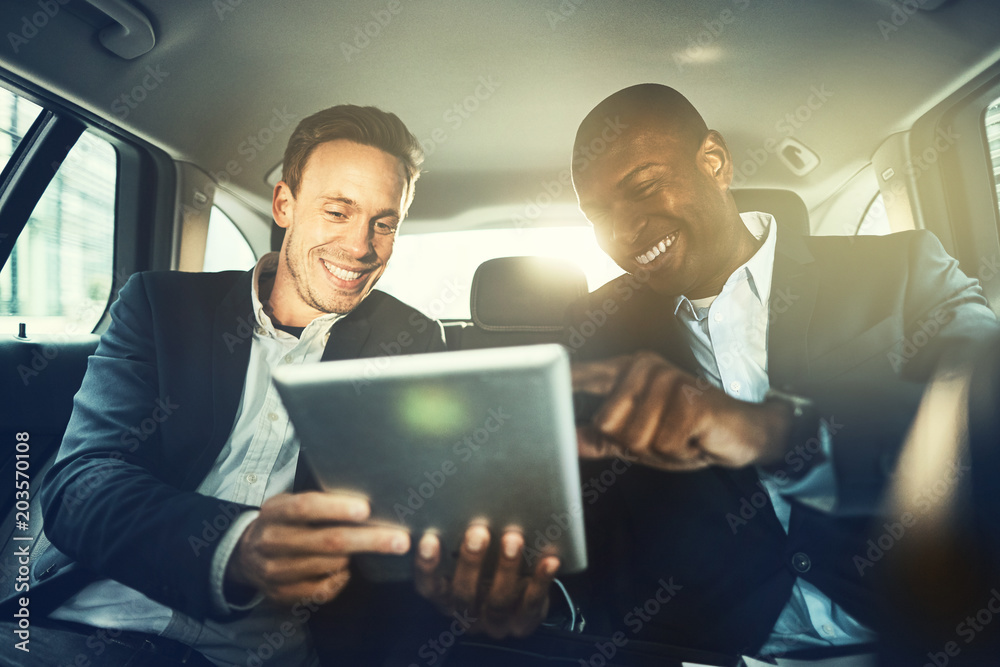 Wall mural smiling business colleagues working online together in a car bac