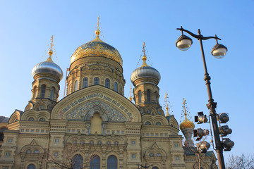 Fototapeta na wymiar Church of the Assumption of the Blessed Virgin Mary in St. Petersburg, Russia. Religious City Landmark, Russian Orthodox Church Building. Exterior View with Ornamental Mosaic Facade and Golden Domes.