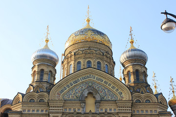 Church of the Assumption of Blessed Virgin Mary in St. Petersburg, Russia. Religious Russian Orthodox Cathedral Building, Exterior View with Facade and Domes from the Street with tree and Lantern.