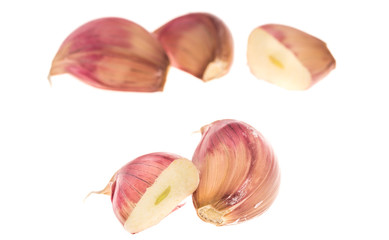 Side view of cloves of garlic and section over white, focus on front