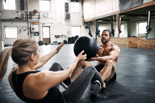Two fit people exercising with a ball at the gym