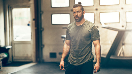 Focused young man in sportswear standing alone in a gym