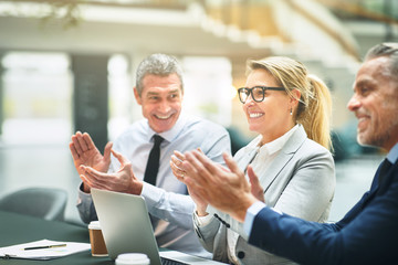 Mature businesspeople smiling and clapping together after a pres