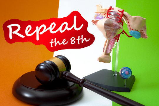 Repeal the eighth amendment of the irish constitution, women rights legislation in ireland and feminism concept with a medical model of the female reproductive system, gavel and flag in the background