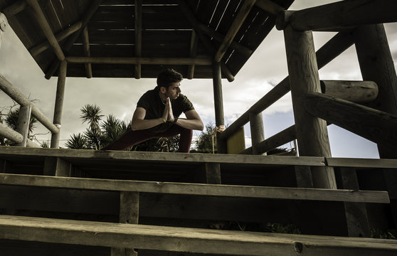 Chico joven realizando ejercicios de yoga en la caba&ntilde;a de madera