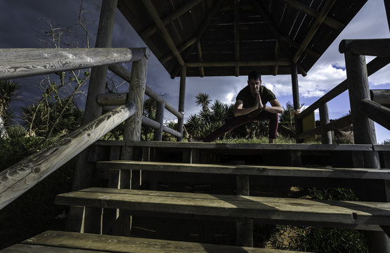 Chico joven realizando ejercicios de yoga en la caba&ntilde;a de madera