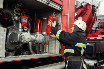 Fototapeta premium Fireman (firefighter) in action standing near a firetruck. Emergency safety. Protection, rescue from danger.