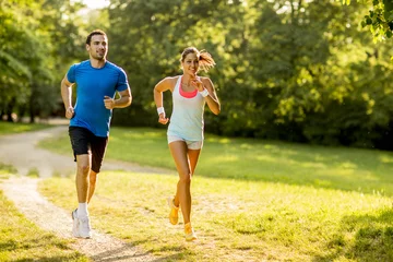 Poster Young couple running in the park on a sunny day © BGStock72