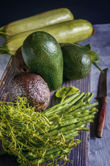 Haas California avocado zucchini thyme herbs and avocado green lie on a wooden table
