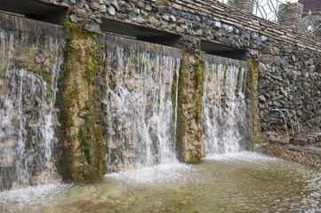Mineral spring. Stream in the SPA. Curative water.  Resort. Waterfalls. Summer. Clear and fresh water on the stone wall 