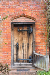 Traditional old wooden oak door with massive iron hinges and door knocker