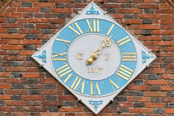 round clock sun dial in blue and gold dated 1817 with brick wall in background