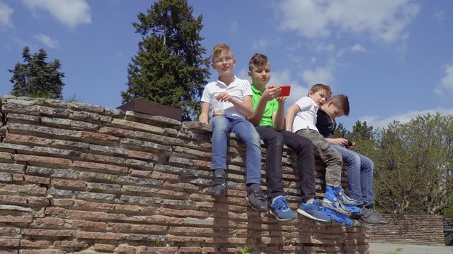 Four boys sits at concrete wall in park