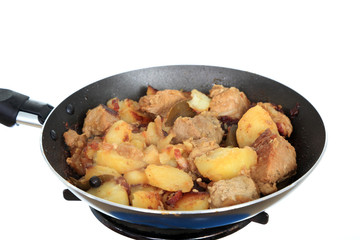 Ziemniaki z kawałkami mięsa, boczku i przyprawami smażone na patelni.