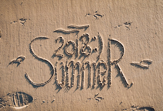 The inscription summer 2018 is written on the sand. The drawing is made by hand. Postcard. Beach holidays.