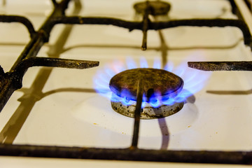 Gas burner on the white kitchen stove