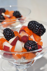 Closeup of fruit salad - apricot, peach, blackberries, raspberries are mixed in glass cups