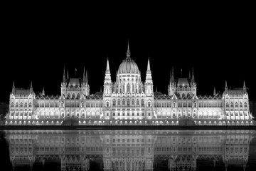 Fototapeta premium beleuchtetes Parlamentsgebäude in Budapest mit Donau im Vordergrund
