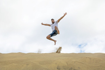 Young tourist jumping on the sand dunes.