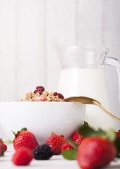 Bowl with cereal and fresh berries and jar of milk