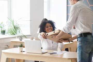 Smiling young african american woman employee taking pizza box from courier sitting at work desk, black office worker ordered meal food delivery service on corporate lunch break sitting at workplace