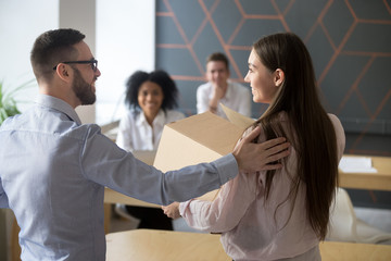 First working day in office concept, friendly male boss welcoming new female employee holding box...