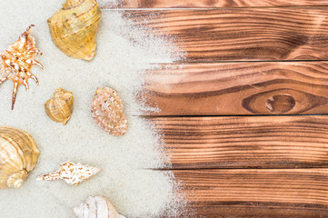 Sand with seashells on the wooden background. Top view. Copy space.