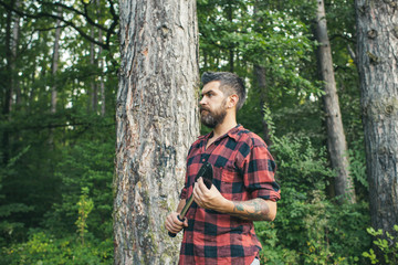 Naklejka na ściany i meble Bearded guy with spade wandering in woods. Side view brutal lumberjack waiting on path. Nature, camping, leisure concept
