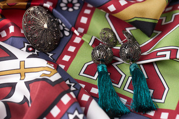 Beautiful silver earrings and a ring on a colorful fabric background. Luxury female jewelry, close-up. Selective focus