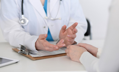 Medicine doctor hand reassuring her female patient closeup. Medicine, comforting  and trusting concept in health care