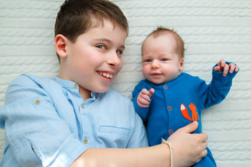 Big brother hugging his newborn baby girl. Toddler kid meeting new sibling