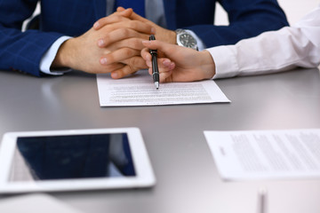 Group of business people and lawyer discussing contract papers sitting at the table, closeup. Businessman is signing document after agreement done
