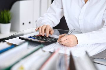 Fototapeta premium Female bookkeeper or financial inspector making report, calculating or checking balance. Internal Revenue Service checking financial document. Audit concept in business