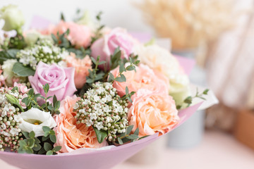pastel orange and lilac bouquet of beautiful flowers on wooden table. Floristry concept. Spring colors. the work of the florist at a flower shop. Vertical photo