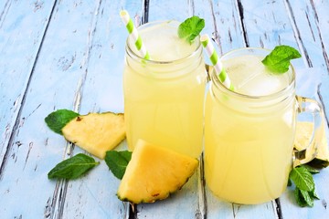 Pineapple juice in mason jar glasses on a rustic blue wood background
