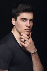 one young handsome man, model wearing t-shirt, simple studio upper body shot, black background.
