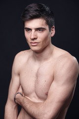 Fototapeta premium one young handsome man, model shirtless, simple studio upper body shot, black background.