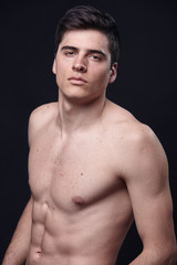 Fototapeta premium one young handsome man, model shirtless, simple studio upper body shot, black background.