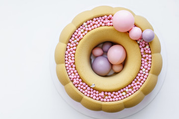 Luxurious round dessert with pink chocolate spheres. Yellow mousse birthday cake with multicoloured sweet sugar balls. Small balls pattern.