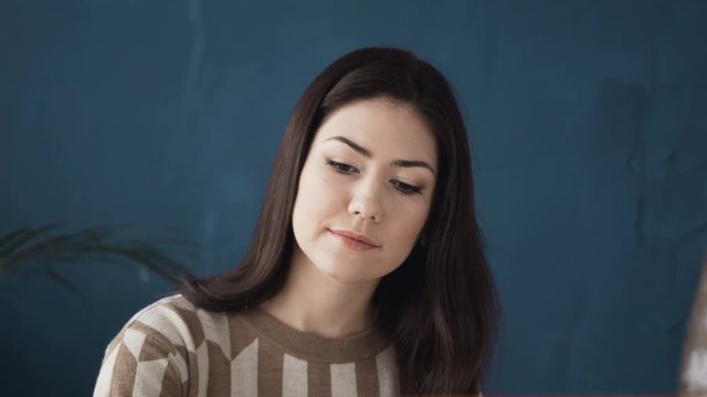 Portrait of beautiful brunette woman painter who paints on a canvas. The artist draws at the easel. The drawing process: professional makeup artist paints a face chart on watercolor paper using board