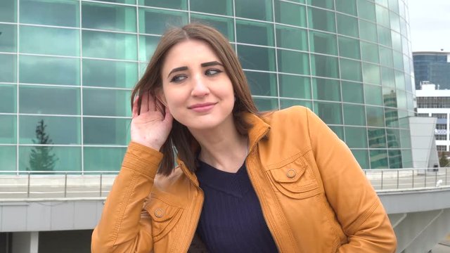 Attractive young woman eavesdropping outdoor in the city in windy day