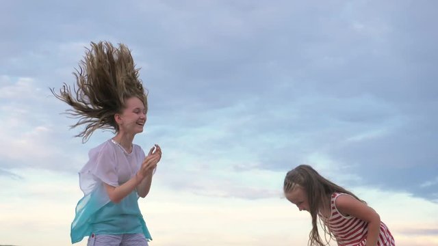 Two children dance and indulge on the beach. Children perform dancing stunts tricks. Hair fluttering in the wind. The kid spin and jump, shake their heads. One girl is a teenager.