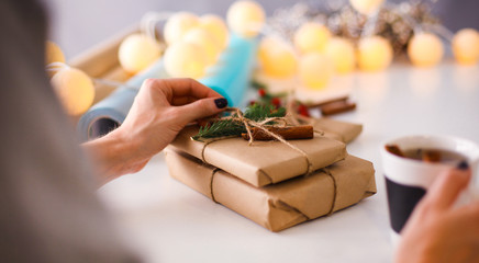 Woman sitting on the desk with christmas gift box. Hands of woman