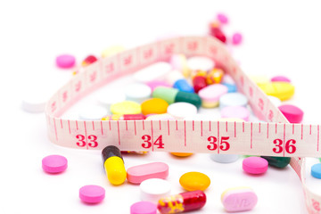 Diet pills and a tape measure on white bacground. Weight loss concept.